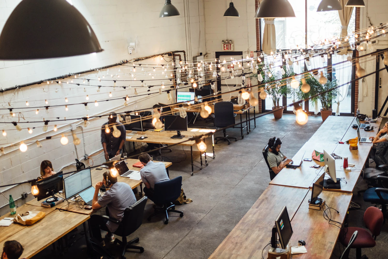 Bureau équipé avec ordinateur, écran et accessoires dans un espace de coworking chaleureux